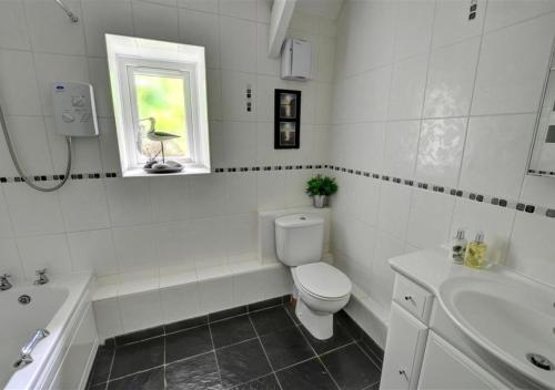 a white bathroom with a toilet and a sink at The Leap in Walton West