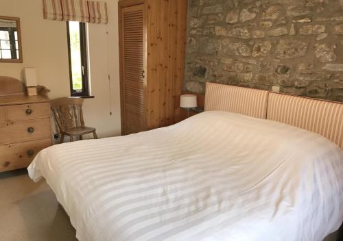 a bedroom with a white bed and a stone wall at Wishing Well in Walton West