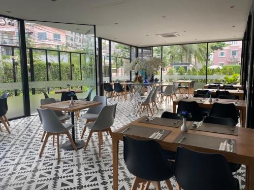 a restaurant with tables and chairs and windows at Almas Hotel Bangkok in Bangkok