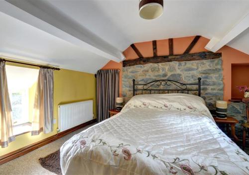 a bedroom with a large bed with a stone wall at Gors in Llanfair Caereinion