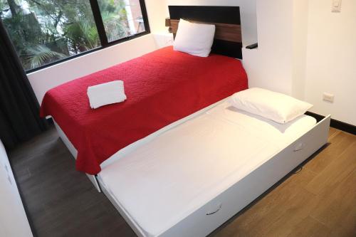 two beds in a small room with a red blanket at Estancia PET FRIENDLY con parqueo y WIFI Gratis in Guatemala