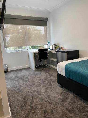 a bedroom with a bed and a desk and a window at Beach Hotel in Burnie