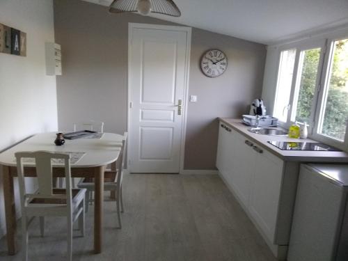 a kitchen with a table and a clock on the wall at Chambre d hotes la Barrière in Channay-sur-Lathan