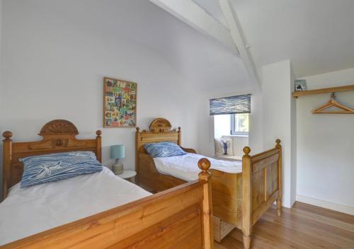 two twin beds in a bedroom with white walls at The Coach House in Bottwnog