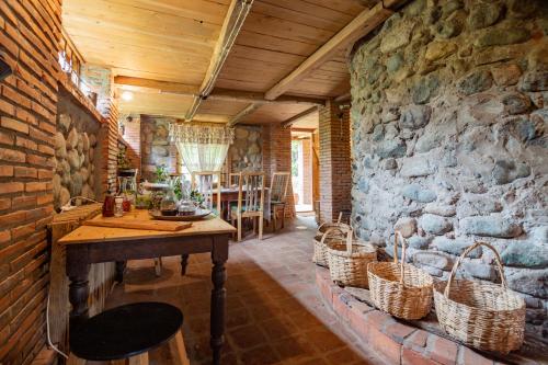 Habitación con pared de piedra, mesa y cestas. en Menabde Winery en Ozurgetʼi