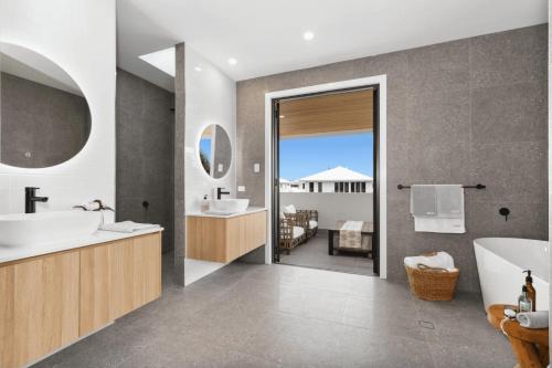 a bathroom with a tub and a sink and a mirror at Beach Life Luxury Escape Kingscliff in Kingscliff