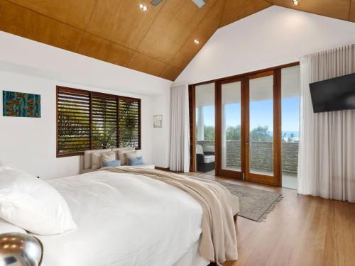 a bedroom with a large bed and large windows at Beachfront On Northpoint in Kingscliff