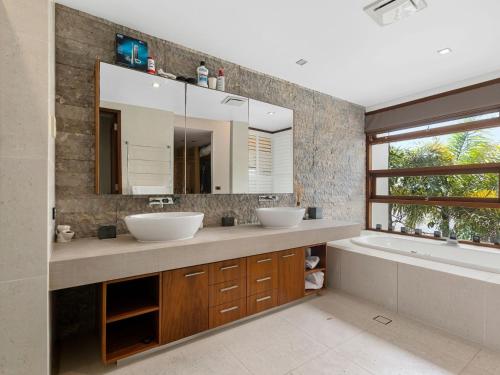 a bathroom with two sinks and a tub and a mirror at Beachfront On Northpoint in Kingscliff