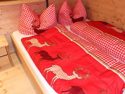 a bed with red and white pillows on it at Feriendorf X-Alp Lodges Ötztal in Sautens