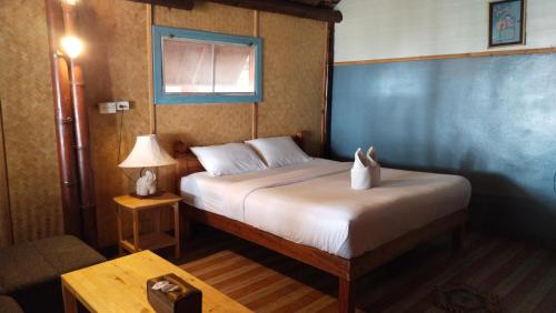 a bedroom with a bed and a table with a lamp at Lazy Hut in Ko Phayam