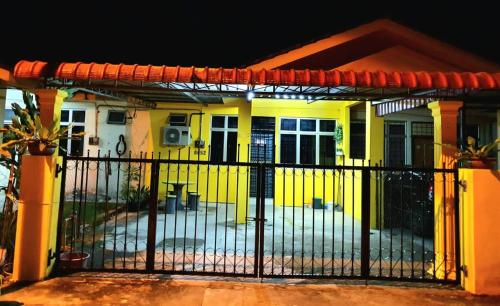 ein gelbes Haus mit einem Tor davor in der Unterkunft LH Alisha Homestay Wangsa Mewangi Gua Musang in Gua Musang