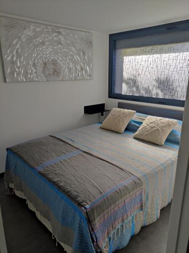 ein Schlafzimmer mit einem Bett mit zwei Kissen und einem Fenster in der Unterkunft L'Orlu Chambres D'Hotes proximité plage in Canet-en-Roussillon