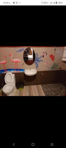 a bathroom with a toilet with flamingos painted on the wall at Lazy Hut in Ko Phayam