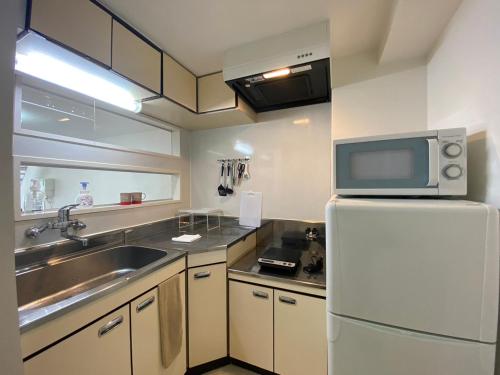 een keuken met een wastafel en een koelkast met een magnetron bij Easy Access to downtown area, Sapporo Dome AMS503 in Sapporo