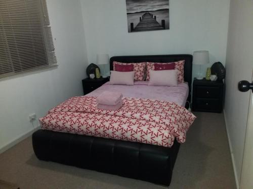 a bedroom with a large bed with a red comforter at The DOLPHIN PLACE in Australind