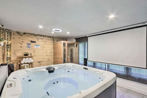 a large white tub in a room with a large screen at Upscale Waterbury Retreat with Indoor Hot Tub! in Waterbury