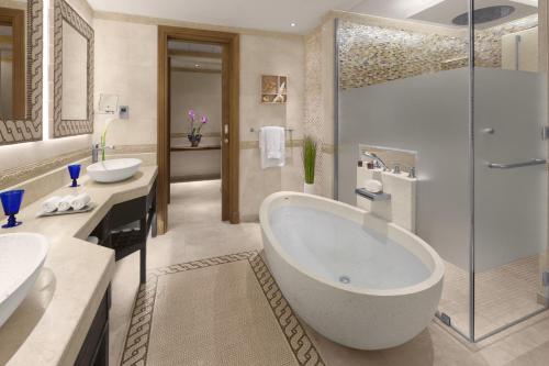 a bathroom with a tub and two sinks and a shower at Banana Island Resort Doha by Anantara in Doha