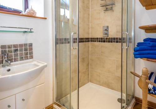 ein Bad mit einer Dusche und einem Waschbecken in der Unterkunft The Barn in Llannor