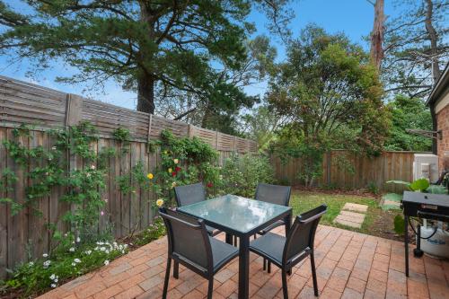 a patio with a table and chairs and a fence at Bungunyah Apartments in Croydon