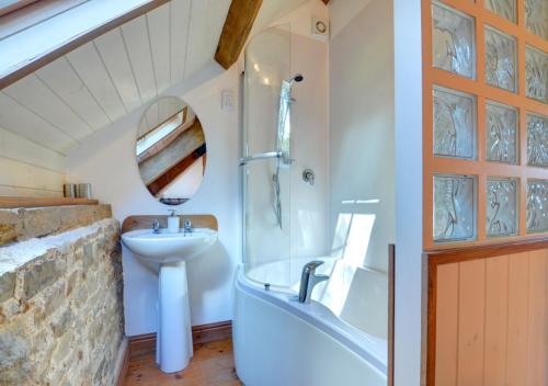 Llansawel的住宿－Threshing Barn，浴室配有盥洗盆、浴缸和镜子