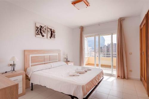 una camera bianca con un letto e una grande finestra di Apartamento Turmalina - Plusholidays a Calpe