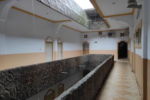 a hallway of a building with a stone wall at Capital O 91650 Hotel Pratama in Kolaka