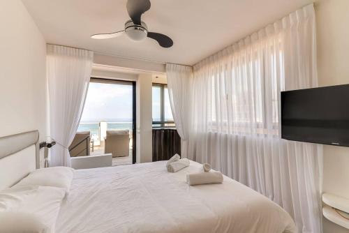 a bedroom with a large white bed with a flat screen tv at Wonderfull duplex 3BR Hakovshim by Holiday-rentals in Tel Aviv