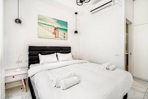 ein weißes Schlafzimmer mit einem Bett mit Handtüchern darauf in der Unterkunft Beautifull 3BR in Masaryk by Holiday-rentals in Tel Aviv