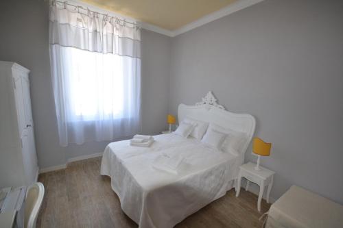 a white bedroom with a white bed and a window at Affittacamere Casa Dane' in La Spezia
