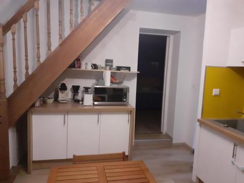 une cuisine avec un comptoir et un four micro-ondes ainsi qu'un escalier dans l'établissement les papyrus avec draps, à Arles
