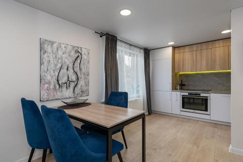 a kitchen with a dining room table and blue chairs at RIVERFRONT 2BD Old Town Apartment by Hostlovers in Kaunas
