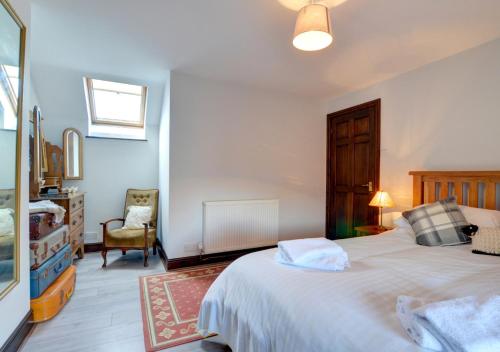 a bedroom with a large white bed and a chair at Old Newton Cottage in Porthcawl