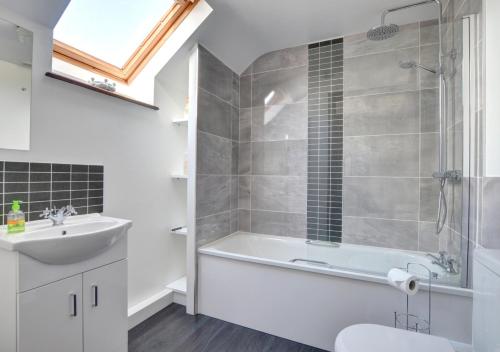 a bathroom with a tub and a sink and a shower at Old Newton Cottage in Porthcawl