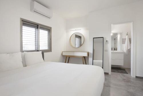 Central 3BR in Ruppin by Holiday-rentals في تل أبيب: غرفة نوم بيضاء مع سرير أبيض ومرآة