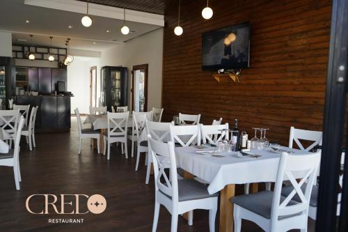 un comedor con mesas blancas y sillas blancas en Hotel Credo en Prizren