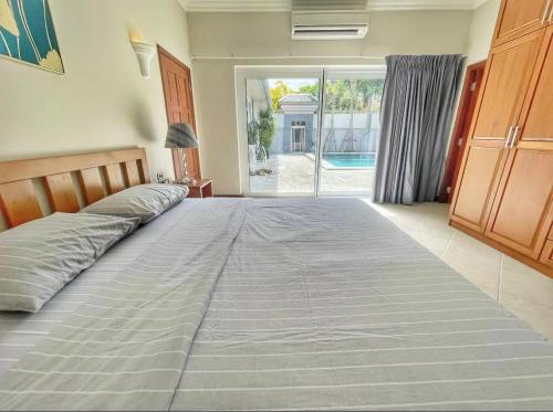 Cette chambre comprend un grand lit et une grande fenêtre. dans l'établissement Pool villas with big garden and near Jomtien beach 600 meters, à Jomtien Beach