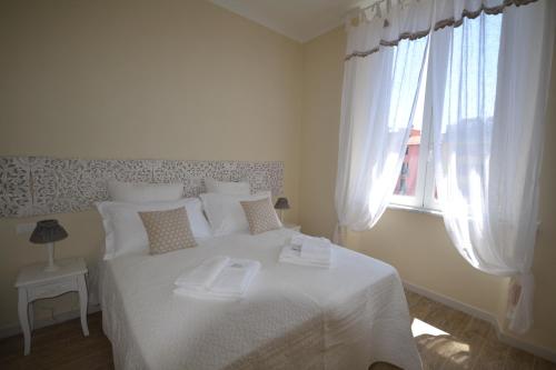 a white bedroom with a white bed with a window at Affittacamere Casa Dane' in La Spezia