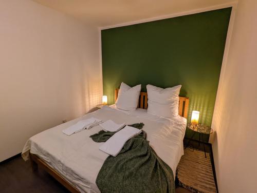 ein Schlafzimmer mit einem großen weißen Bett und einer grünen Wand in der Unterkunft HejU - Luxury Aussicht - Kingsize Bed - Kitchen - Bathtub in Lübeck