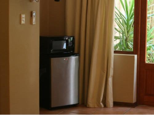 a microwave on top of a refrigerator next to a window at River Bank Lapa in Upington