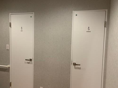 3 portes blanches dans une salle de bains avec le numéro 4 dans l'établissement SORAYADO 宙宿, à Tsuru 