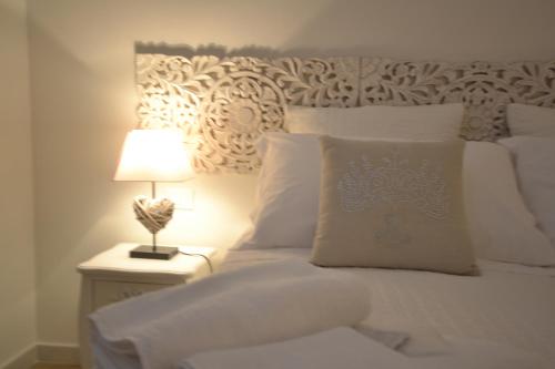 a white bed with a lamp on a night stand at Affittacamere Casa Dane' in La Spezia