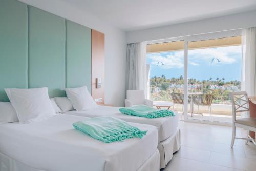 2 camas blancas en una habitación con vistas al océano en Iberostar Playa Gaviotas All Inclusive, en Morro del Jable