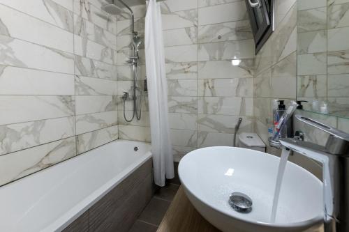 a white bathroom with a sink and a bath tub at Hotel @Syngrou Fix in Athens