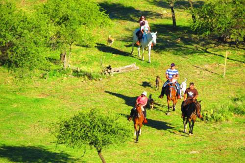 a group of people riding horses in a field at Los Ancares Resort in Mina Clavero