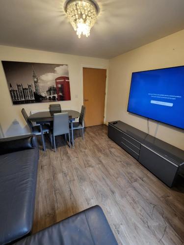 a room with a table and a large screen television at Beautiful 4 bedroom home with private parking in West Thurrock