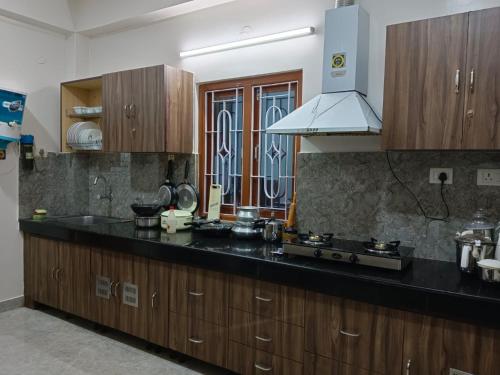 uma cozinha com um balcão preto e armários de madeira em Sweet Mango Tree Homestay em Port Blair