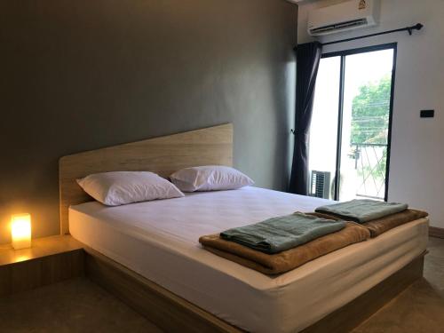 a bedroom with a bed with two pillows and a window at Newman hotel in Ban Khlong Ha