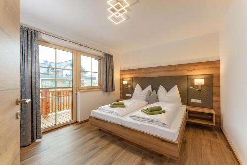 sypialnia z dużym łóżkiem i dużym oknem w obiekcie Appartements Die Ramsauerin w mieście Ramsau am Dachstein