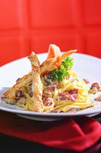 a plate of food with pasta and bread at CROWN PRINCE Hotel Surabaya Managed by Midtown Indonesia in Surabaya