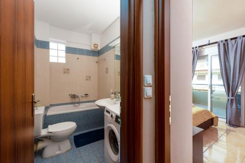 uma casa de banho com um lavatório e uma máquina de lavar roupa em Eleni's modern apartment em Volos